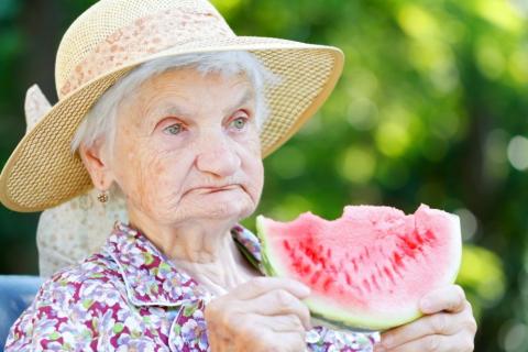 Older woman who eats a piece of watermelon